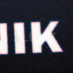 Nahaufnahme eines Buchstabens auf schwarzem Hintergrund mit strukturierten Details.