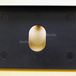 Detaillierte Ansicht einer schwarzen Halterung mit einem ovalen Ausschnitt in der Mitte und runden Gummifüßen an den Ecken.