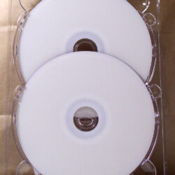 Eine transparente CD-Hülle mit zwei leeren, weißen CDs, die auf einem goldfarbenen Hintergrund liegen.