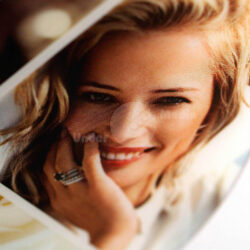 Nahaufnahme eines lächelnden Gesichts mit blonden Haaren und einer Hand, die an die Wange gelegt ist, auf einer CD.