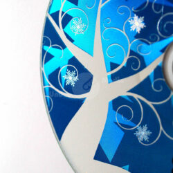 Detailaufnahme einer CD mit winterlichem Design, featuring weiße Schneeflocken und geschwungene Äste auf azurblauem Hintergrund.