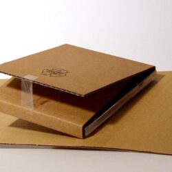 Eine stapelbare Kartonverpackung, die eine flache und eine aufklappbare Schachtel zeigt.