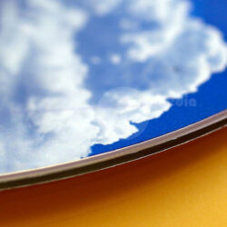 Nahaufnahme eines bunten Designs mit Himmel und Wolkenmotiven auf einem glänzenden Material.