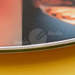 Nahaufnahme der Kante eines farbigen Plattencovers auf gelbem Hintergrund.