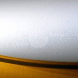 Nahaufnahme der glatten, weißen Oberfläche eines Musikinstruments mit einem gelben Rand.