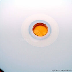 Naheinstellung eines Tayio Yuden DVD mit orangenem Discloch und weißer bedruckbarer Oberfläche.