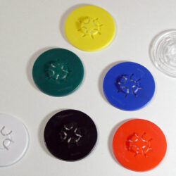 Eine Anordnung von bunten Kunststoffscheiben in verschiedenen Farben auf einem weißen Hintergrund.