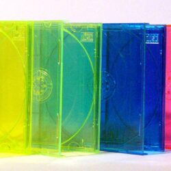 Eine Reihe von transparenten CD-Hüllen in verschiedenen Farben, darunter Gelb, Blau, Grün und Pink, auf einem weißen Hintergrund.
