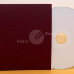 CD-Hülle und -Scheibe:::Eine burgunderfarbene CD-Hülle liegt neben einer leeren, transparenten CD.