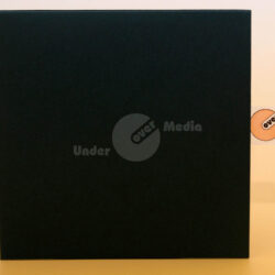 Abbildung einer schwarzen Box mit dem Logo "Under Over Media" und einem kleinen Aufkleber auf der Seite.