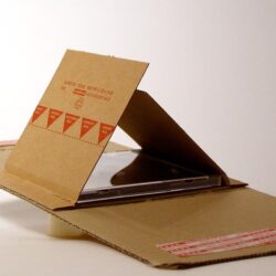 Eine geöffnete Kartonverpackung, die eine CD-Hülle zeigt, mit abgerundeten Kanten und Sicherheitsaufklebern.