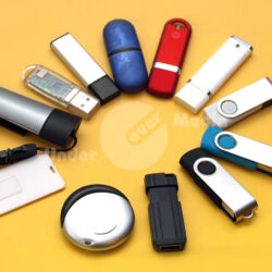 Eine Auswahl an verschiedenen USB-Sticks auf gelbem Hintergrund, einschließlich Farben wie Blau, Rot, Weiß und Schwarz.