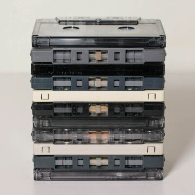 Ein Stapel von klassischen Audiokassetten in verschiedenen Farben, auf einem weißen Hintergrund.