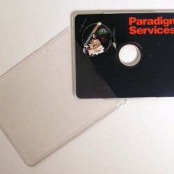 Eine schwarze Diskette mit dem Logo von Paradigm Services, neben einer transparenten Hülle.