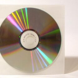 Eine reflektierende CD, die in einer transparenten Hülle steht, mit bunten Lichtstrahlen auf der Oberfläche.