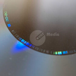 Detailaufnahme eines CD-Glasmaster, die Lichtreflexionen und blau-grüne Farbspektren zeigt.