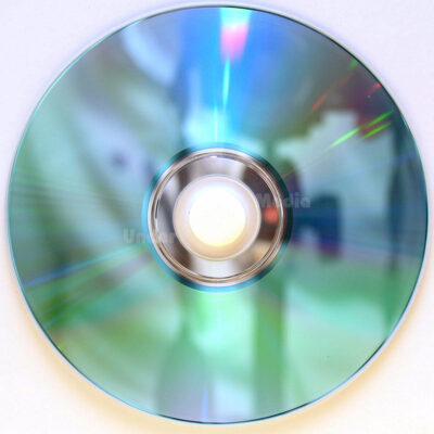 Eine reflektierende CD zeigt eine Vielzahl von Farben in einem schimmernden Muster, aufgenommen von oben.