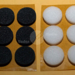 Sechs schwarze und sechs weiße runde Schaumstoffpads auf einem Kartonblatt angeordnet.