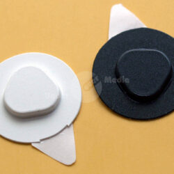 Zwei haftfähige Pads in Weiß und Schwarz auf einem gelben Hintergrund.