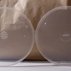 Eine transparente Hülle für Brillen mit einem stilisierten Logo, auf einem neutralen Hintergrund.