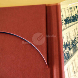 Nahaufnahme eines roten Buchrückens mit einem geschwungenen Schnitt und historischer Fotografie auf dem Cover.