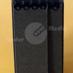 Seitenansicht einer schwarzen, rechteckigen Box mit einem Schlitz und dekorativen Elementen an der Oberkante.