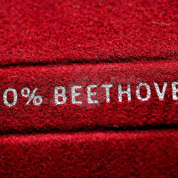 Nahaufnahme von einem roten Stoff mit dem Aufdruck "100% BEETHOVEN" in silberner Schrift.