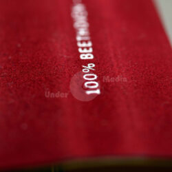 Detailansicht der Stoffoberfläche mit dem Aufdruck "100% ROTE BEETE" in weiß.