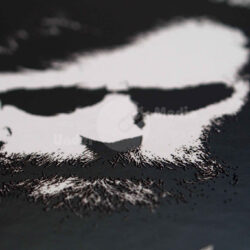 Detailaufnahme eines künstlerischen Portraits mit markantem Gesicht und Bart auf schwarzem Hintergrund.