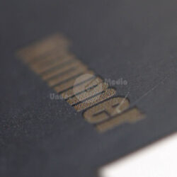 Detailaufnahme eines Kartenmotivs mit schimmerndem Schriftzug auf dunklem Hintergrund.