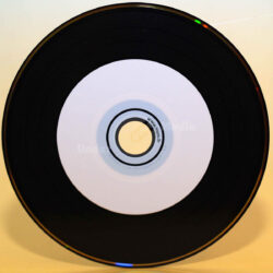 CD in Vinylplatten-Optik, mit einem zentralen, hellen Label und einem schwarzen Rand.