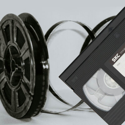 Detailaufnahme einer Filmrolle und einer Videokassette auf einem hellen Hintergrund